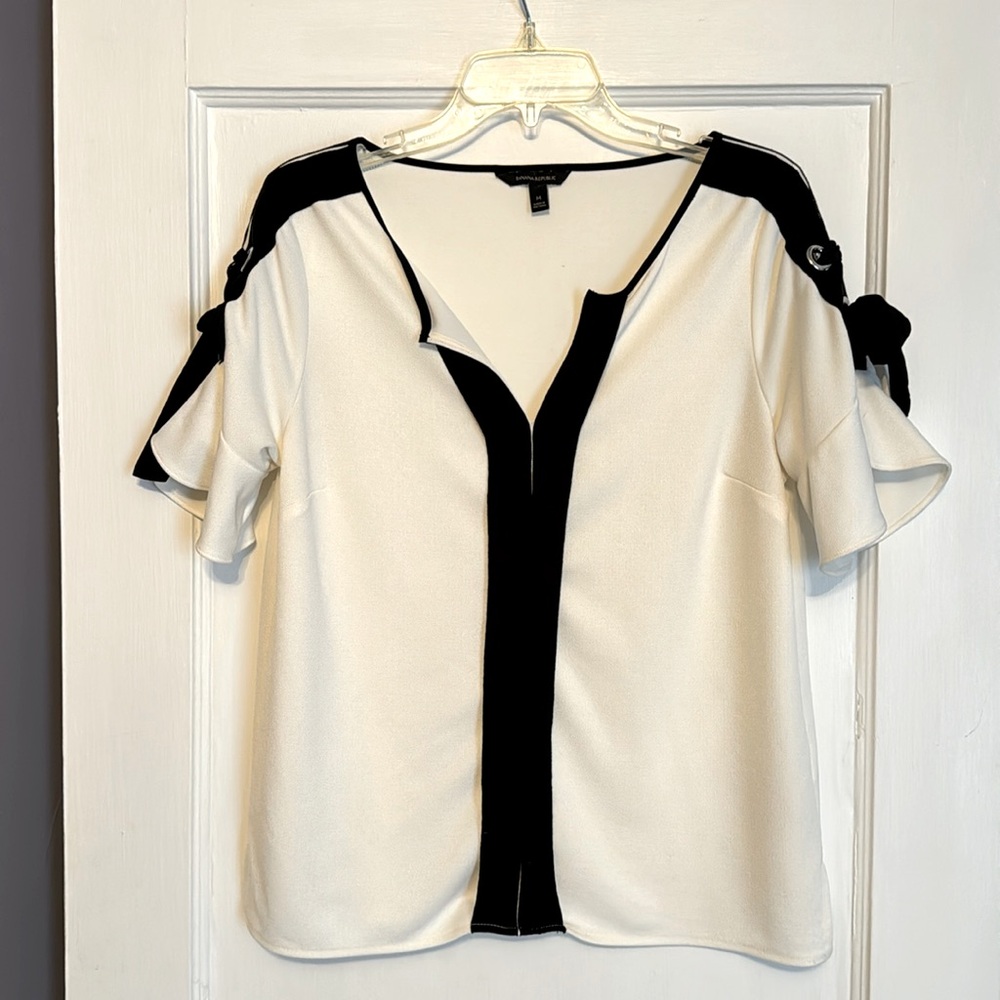 Short flutter sleeve top with v-neck and grommet and tie sleeve detail.
